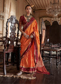 A vibrant orange Tussar silk saree featuring elegant traditional weaving work and a matching blouse.