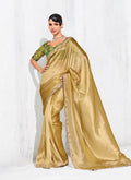 Woman wearing a glamorous golden silk saree with a vibrant green embroidered blouse.