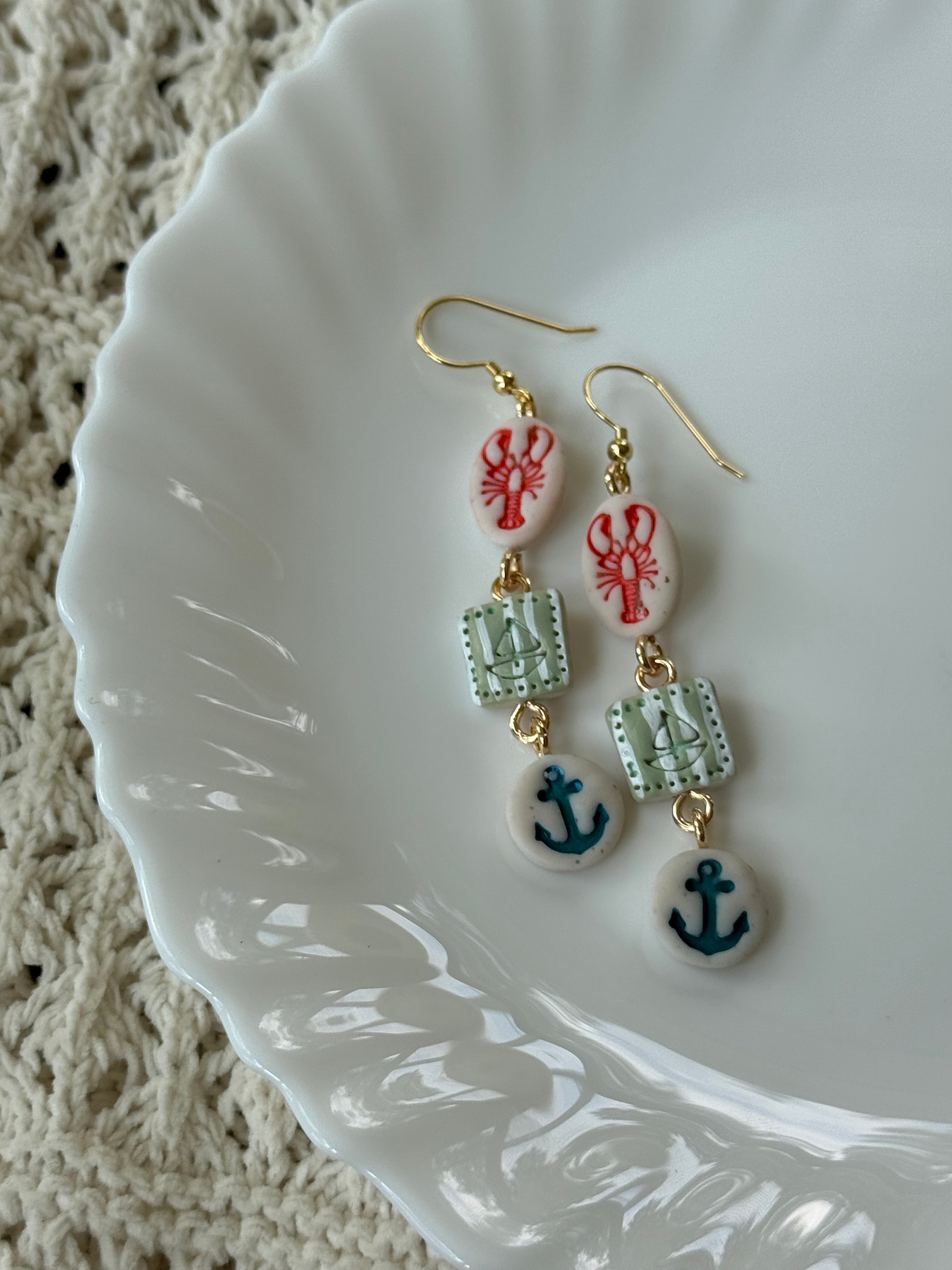 Nautical-themed multi-colored polymer clay earrings with gold accents.