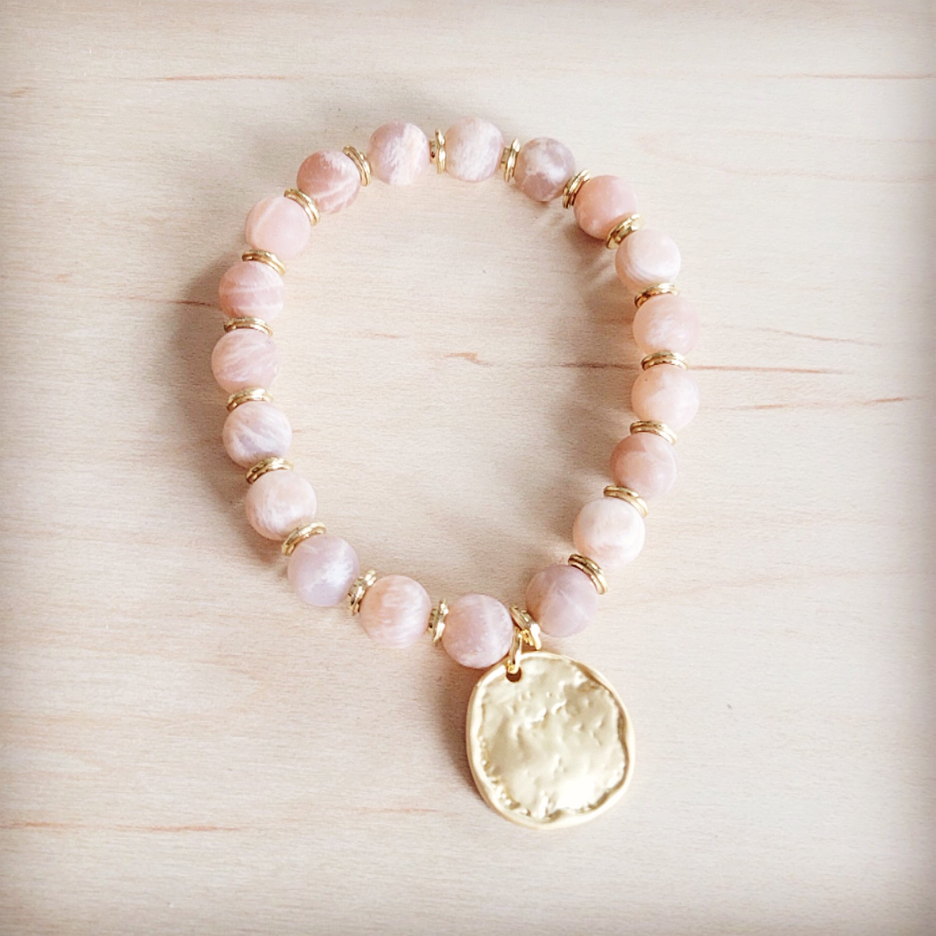 Frosted sunstone bead stretch bracelet with a decorative matte gold-tone charm