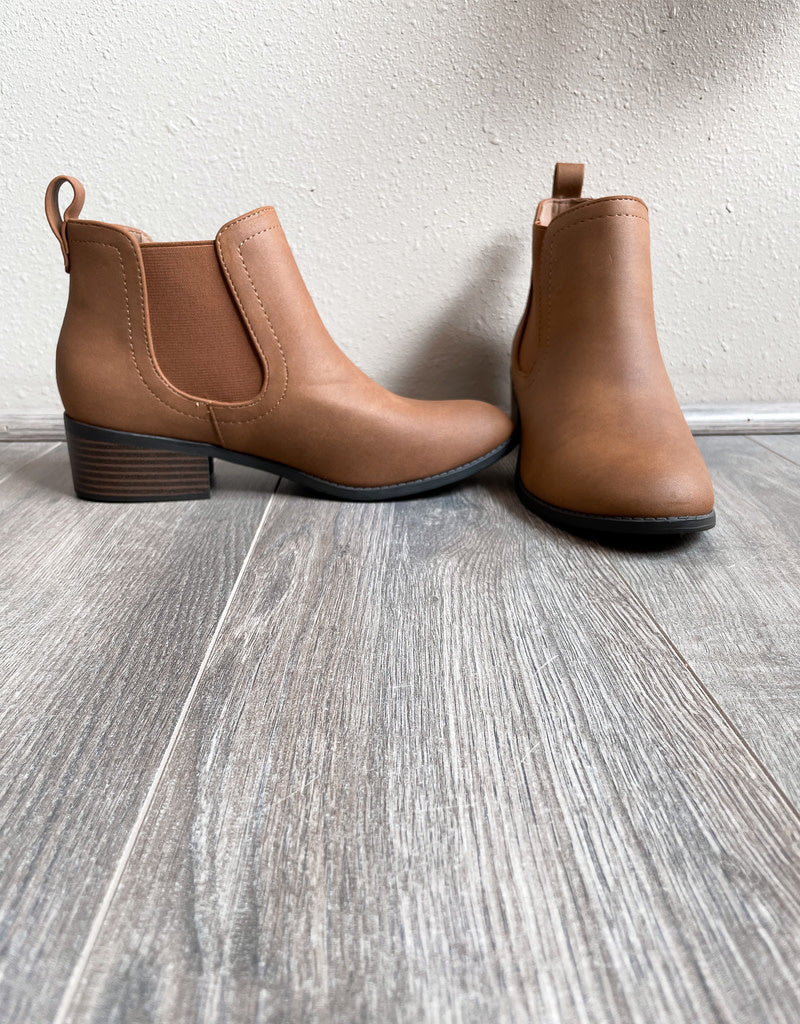 A pair of classic cognac leather Rita Booties featuring a minimalist design and sturdy stacked heel.