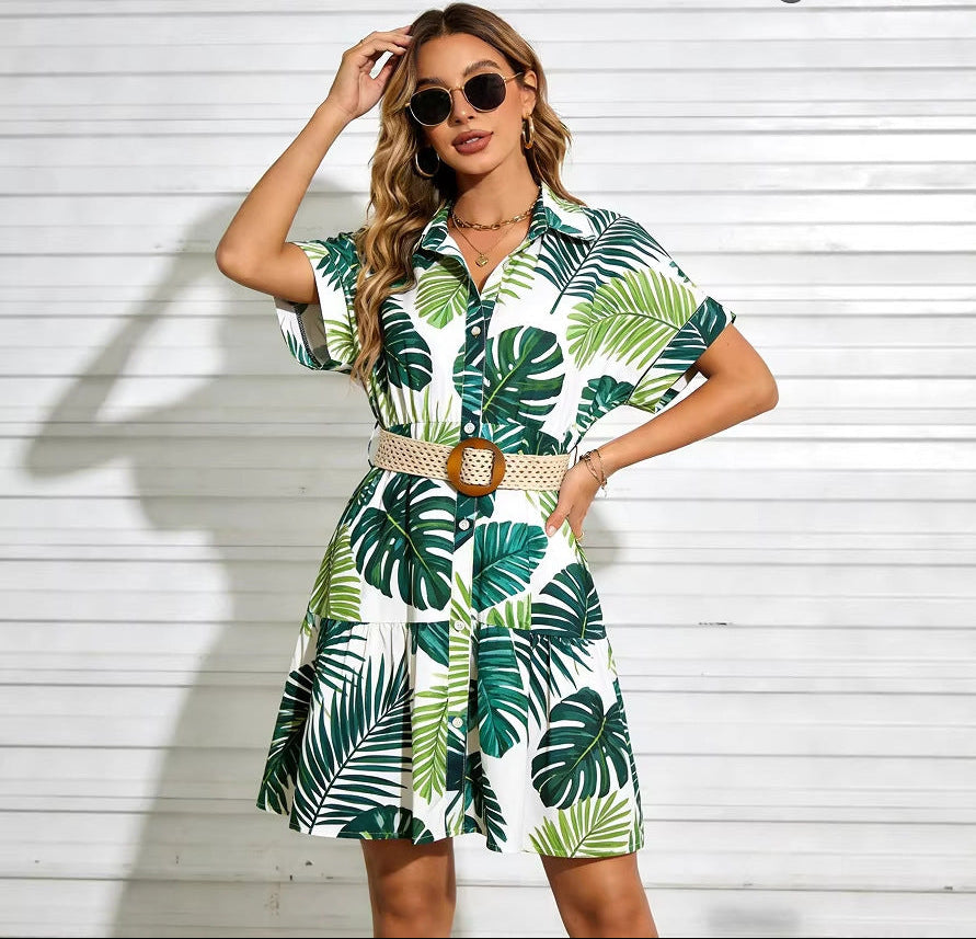 A model wearing a short sleeve button-down mini dress with a woven belt, available in botanical and daisy print options.