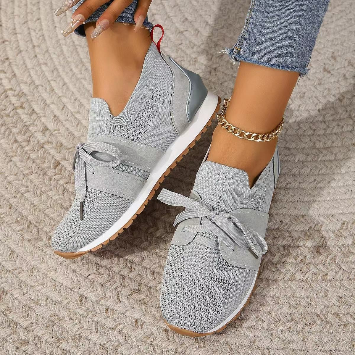 A pair of comfortable grey lace-up mesh walking flats on a textured background.