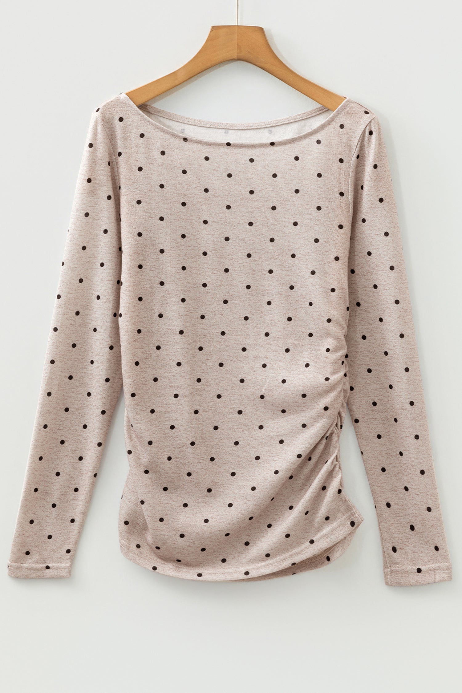 A woman wearing a polka dot long sleeve top with a boat neck and knit texture.