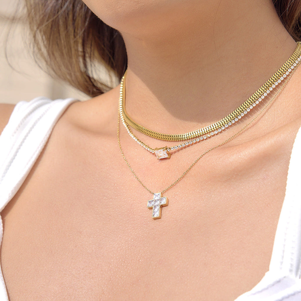 Minimalist gold-tone stainless steel cross necklace with a clear zircon stone pendant.