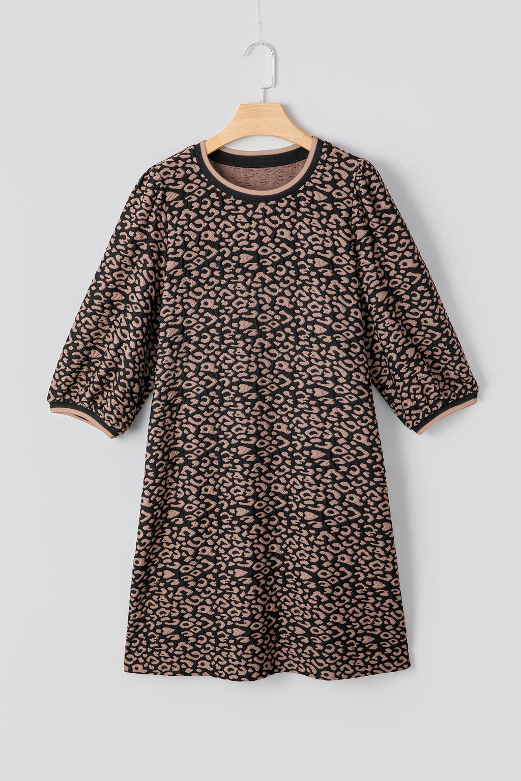 Leopard print dress on a hanger against a light gray background