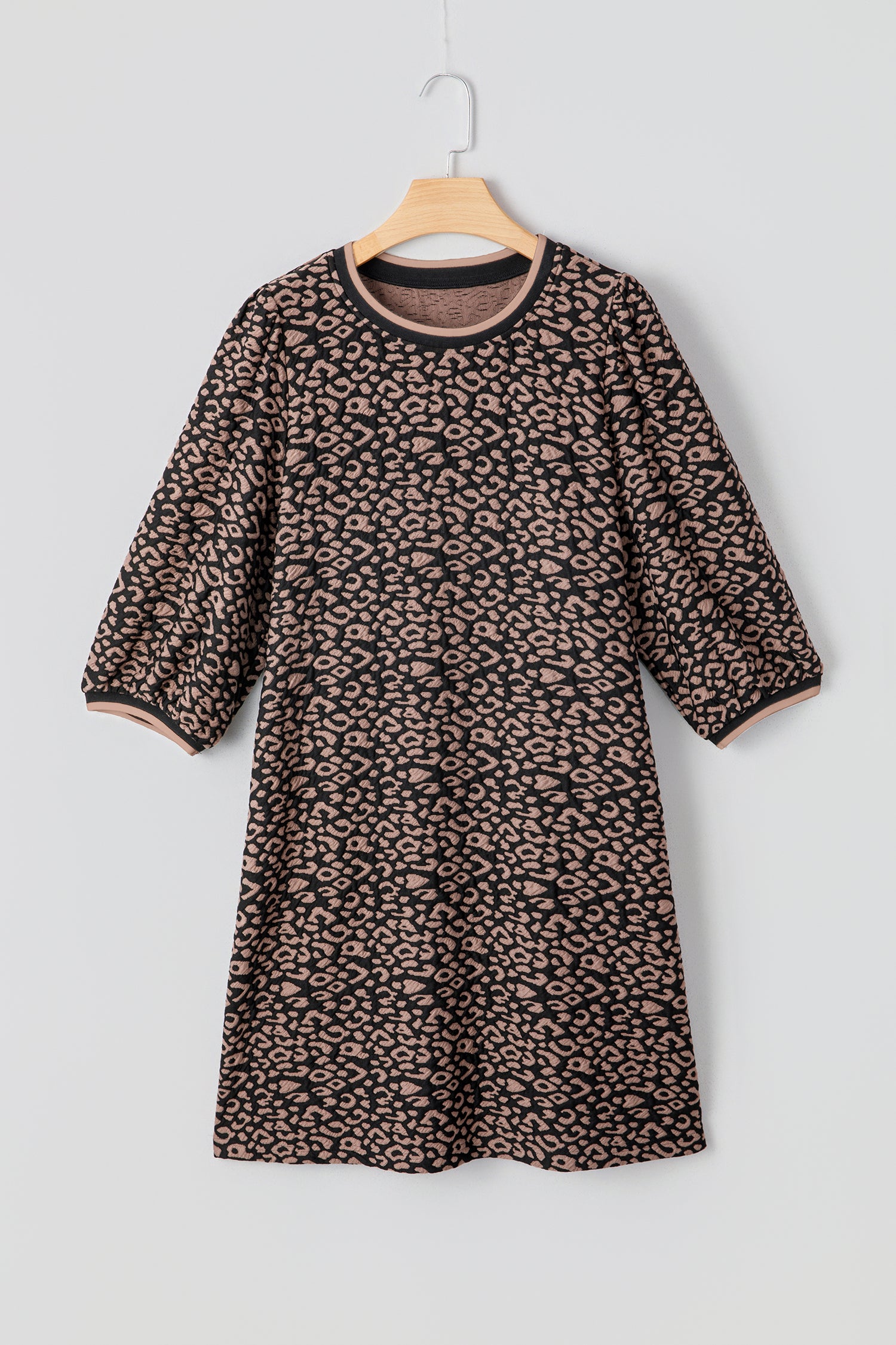 Leopard print dress on a hanger against a light gray background