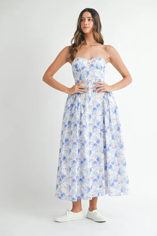 Model wearing a white and blue floral midi dress with a sweetheart neckline.