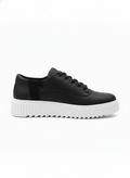 A pair of sleek black men's sneakers with a thick, ridged white platform sole, shown from the side against a white background.