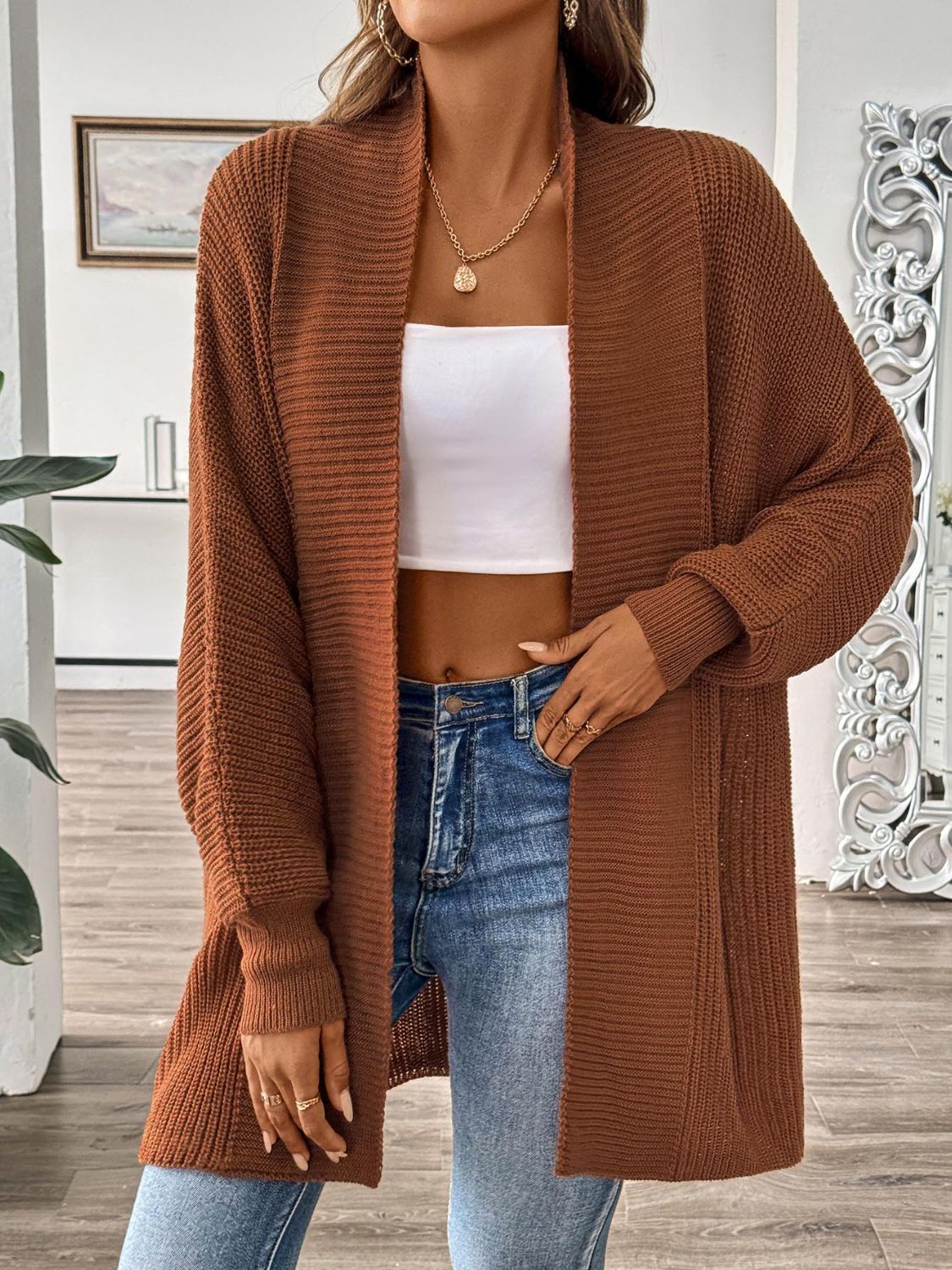 Model wearing a rust-colored long sleeve open front ribbed knit cardigan