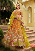 Close up of an amber and lime-green silk lehenga choli featuring heavy decorative embroidery.