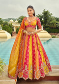 Woman wearing a heavy embroidered rani pink silk lehenga choli with multicolored accents
