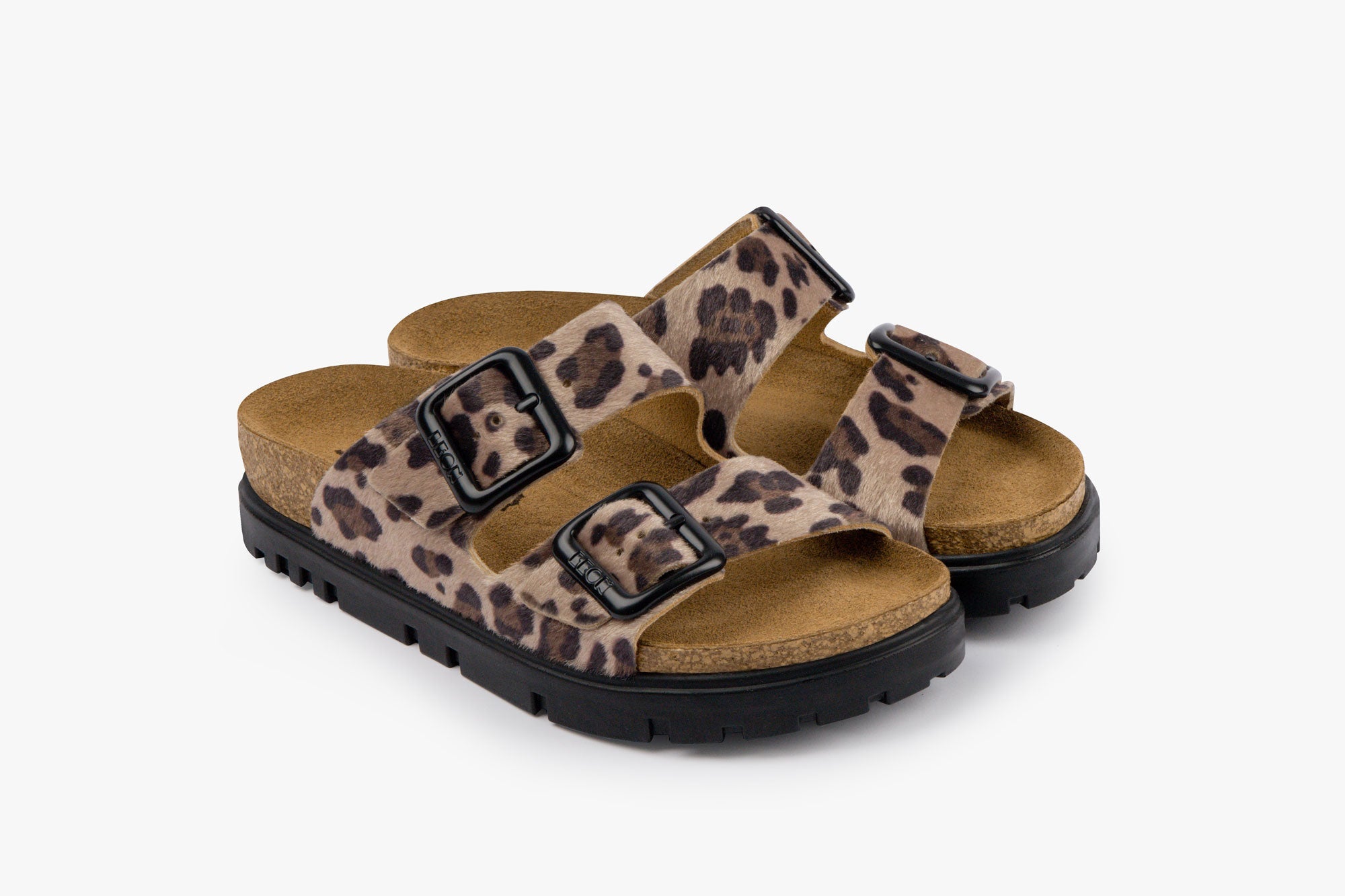A pair of women's leather slide sandals with a leopard print pattern, black adjustable buckles, and a cork-style footbed.