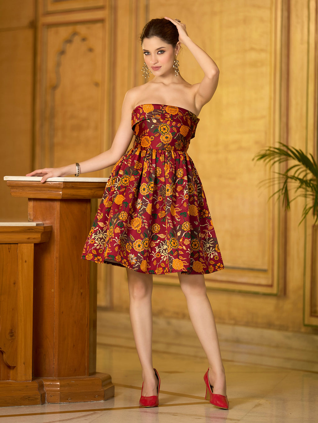 A maroon strapless mini dress featuring gold floral jacquard weaving and zari accents.