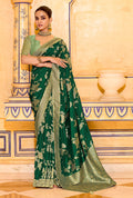 A dark green faux crepe silk saree with detailed zari weaving patterns