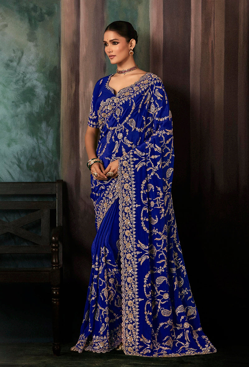 A stunning royal blue faux crepe saree with heavy embroidered borders and matching blouse for wedding occasions.