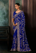 A stunning royal blue faux crepe saree with heavy embroidered borders and matching blouse for wedding occasions.
