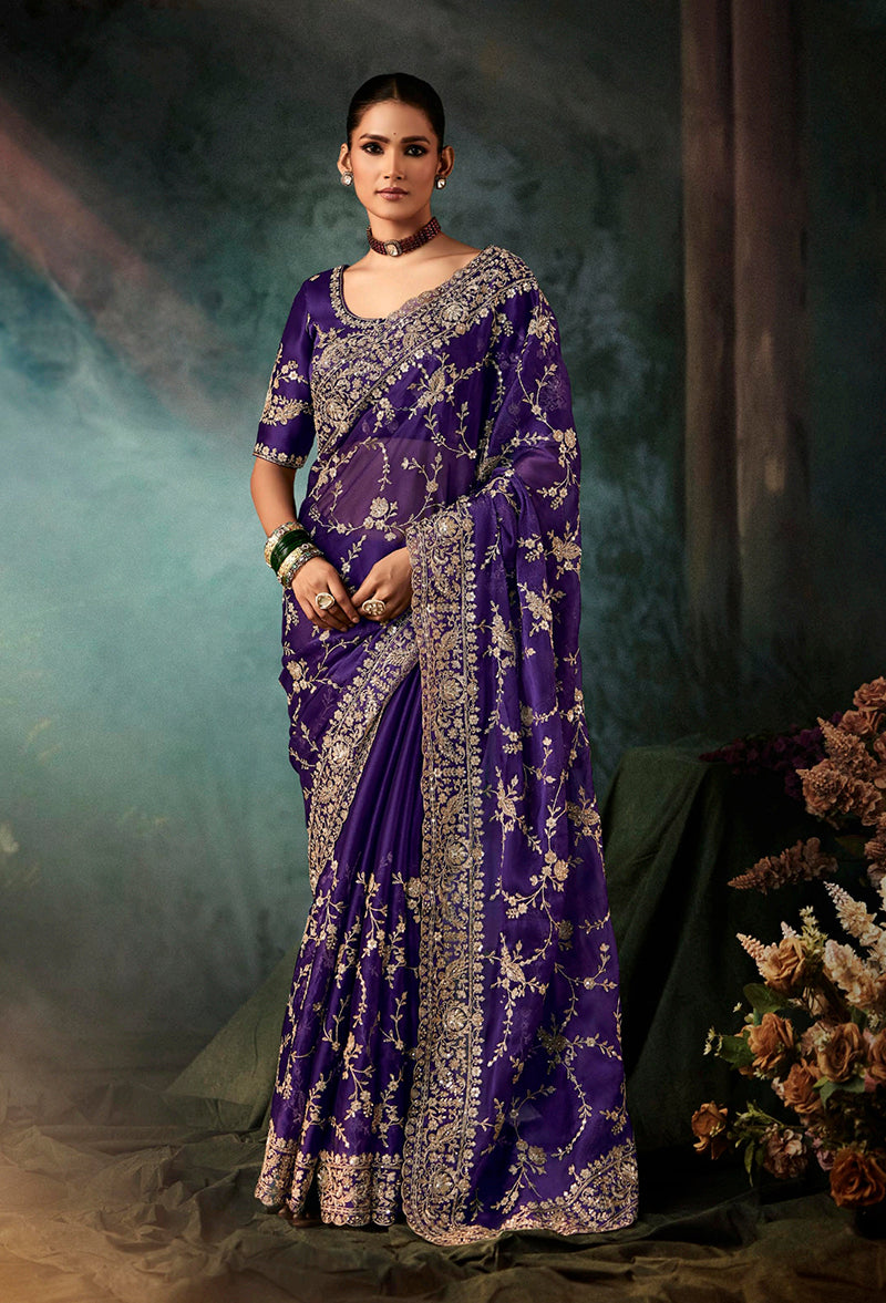 Model wearing a purple faux crepe saree with heavy embroidered border and matching blouse