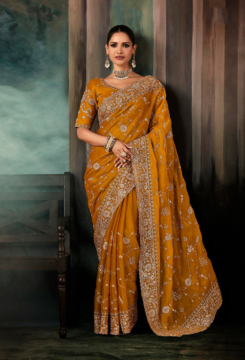 Bright orange embroidered wedding saree with a heavy border, perfect for festivals and receptions.