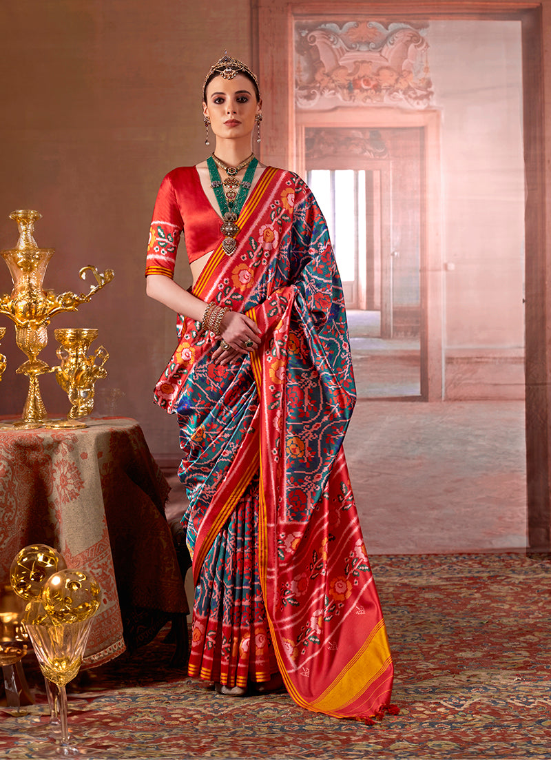 Teal silk blend saree featuring vibrant Patola prints paired with a red blouse