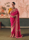 A stunning Rani Pink faux khadi georgette saree featuring intricate Bandhej tie-dye and designer weaving work.