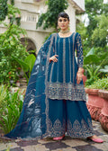Woman wearing a peacock blue embroidered chinnon palazzo kameez with mirror work detail