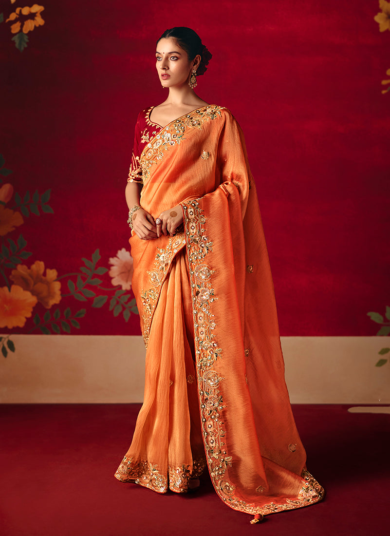 Woman wearing a rust fancy fabric saree with detailed embroidery and sequins