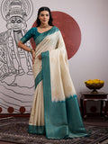 A cream and teal handloom silk blend saree with intricate weaving patterns.