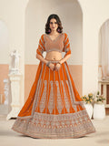 Woman wearing an orange faux georgette embroidered lehenga choli set with matching dupatta