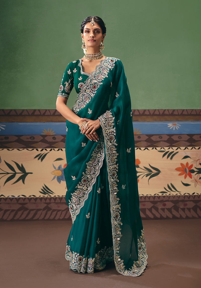 Deep teal fancy fabric saree featuring detailed embroidery and an unstitched blouse.