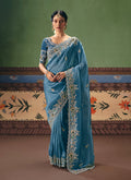 A close-up of a sky blue fancy fabric saree adorned with intricate embroidery, pearls, and sequins.