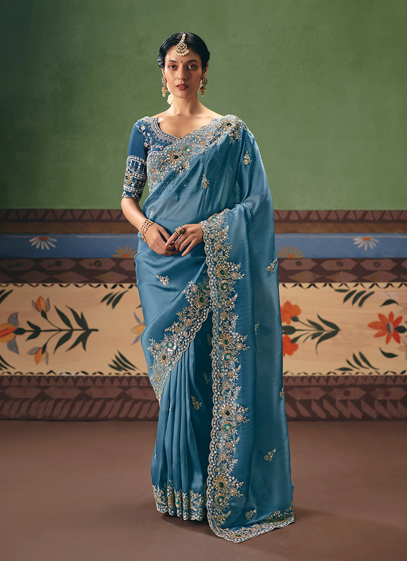 A close-up of a sky blue fancy fabric saree adorned with intricate embroidery, pearls, and sequins.