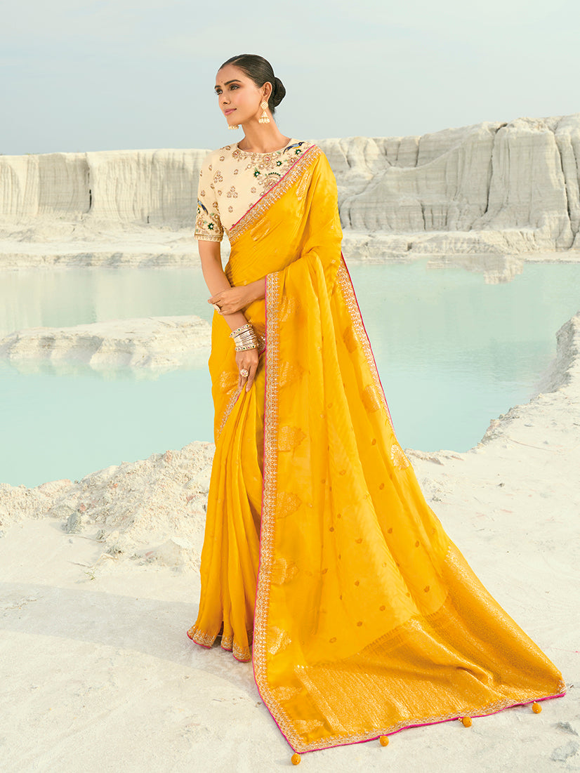 A vibrant yellow organza and satin blend saree with modern embroidery.