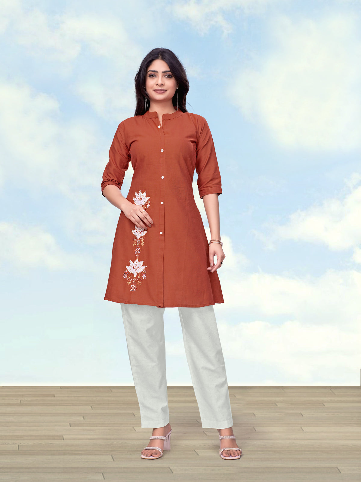 Woman wearing a Rust Cotton Flex kurta set with intricate embroidery on the neckline.