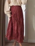 Model wearing a dusty rose ruched elastic waist midi skirt paired with a beige top and strappy heels