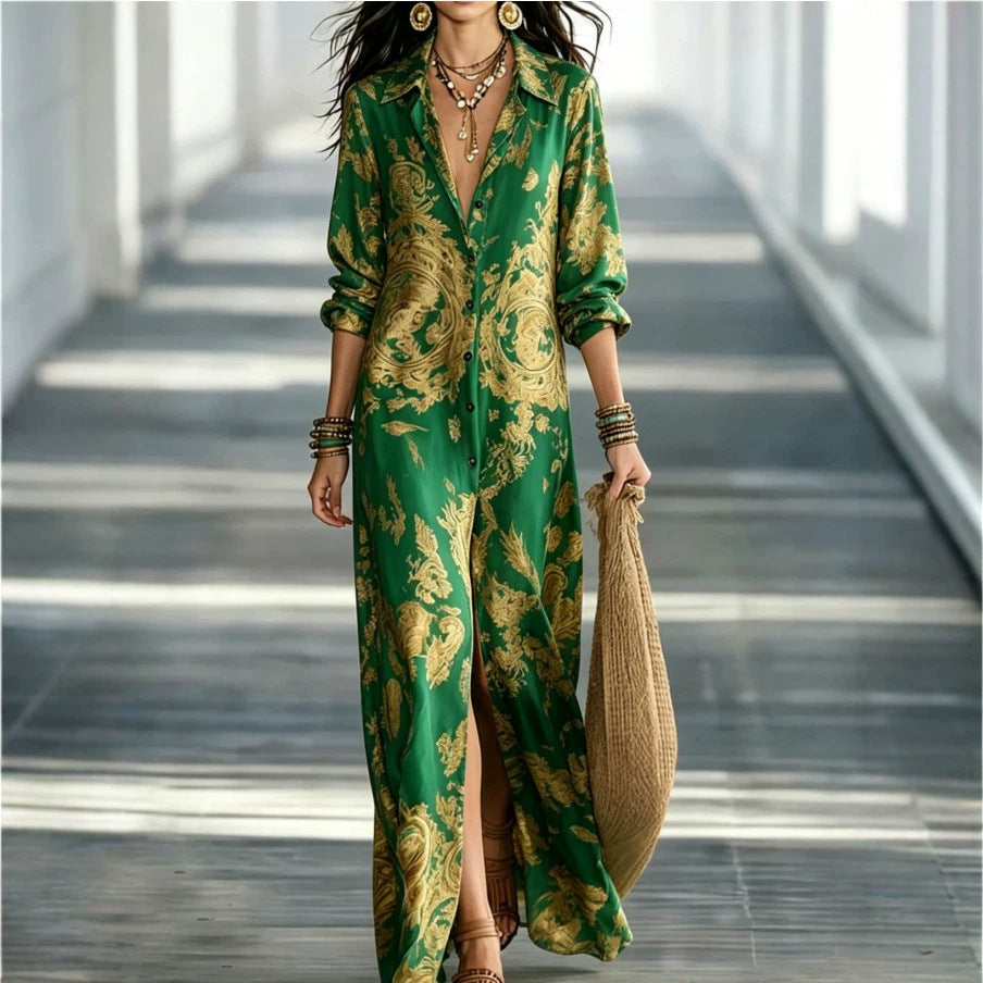 A woman models a green satin-like maxi dress with a gold baroque pattern, featuring a split leg and a deep V-neckline. She is walking in a modern, sunlit corridor, holding a straw bag.