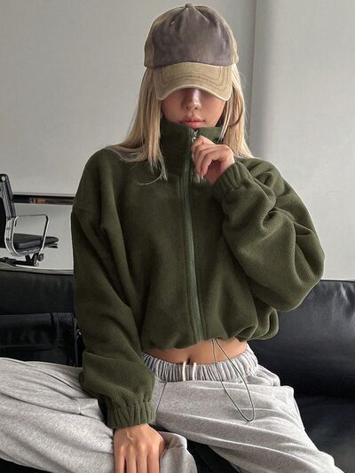 Woman wearing a stylish olive green long-sleeve cropped zip-up jacket.