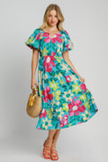 Model wearing a flowy floral print midi dress with puff sleeves and a tiered hem