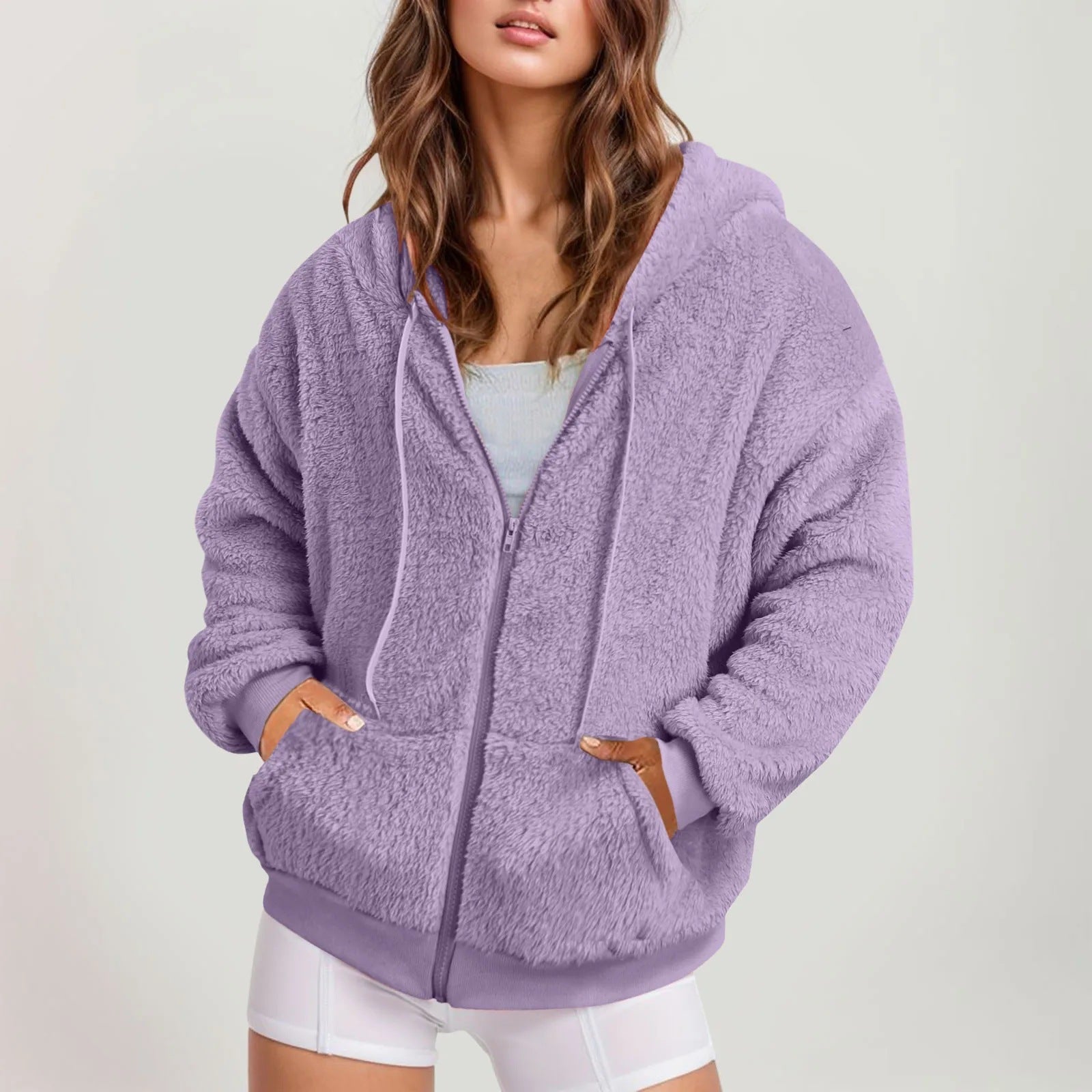 A woman wearing a fuzzy purple fleece zip-up hoodie with two front pockets.