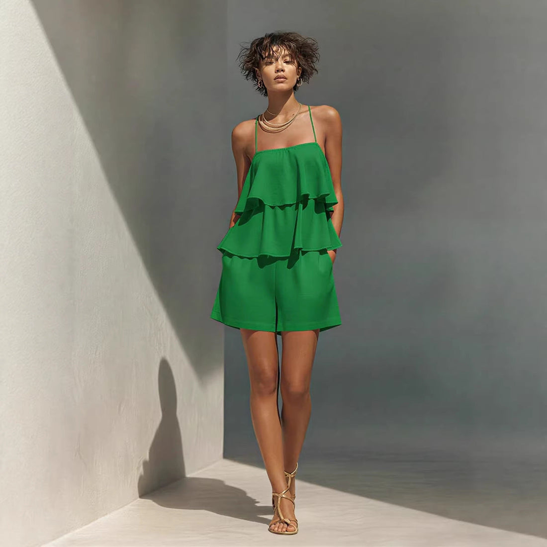 A woman wearing a two-piece set featuring a green multi-layer ruffle camisole and matching shorts.