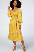Model wearing a yellow floral print midi dress with a square neckline and smocked bodice.