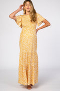 A pregnant woman wearing a yellow floral print maternity maxi dress with a smocked bodice and flutter sleeves, standing against a neutral background.