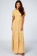 A woman wearing a yellow floral print maxi dress with smocked bodice and tiered pleated hem