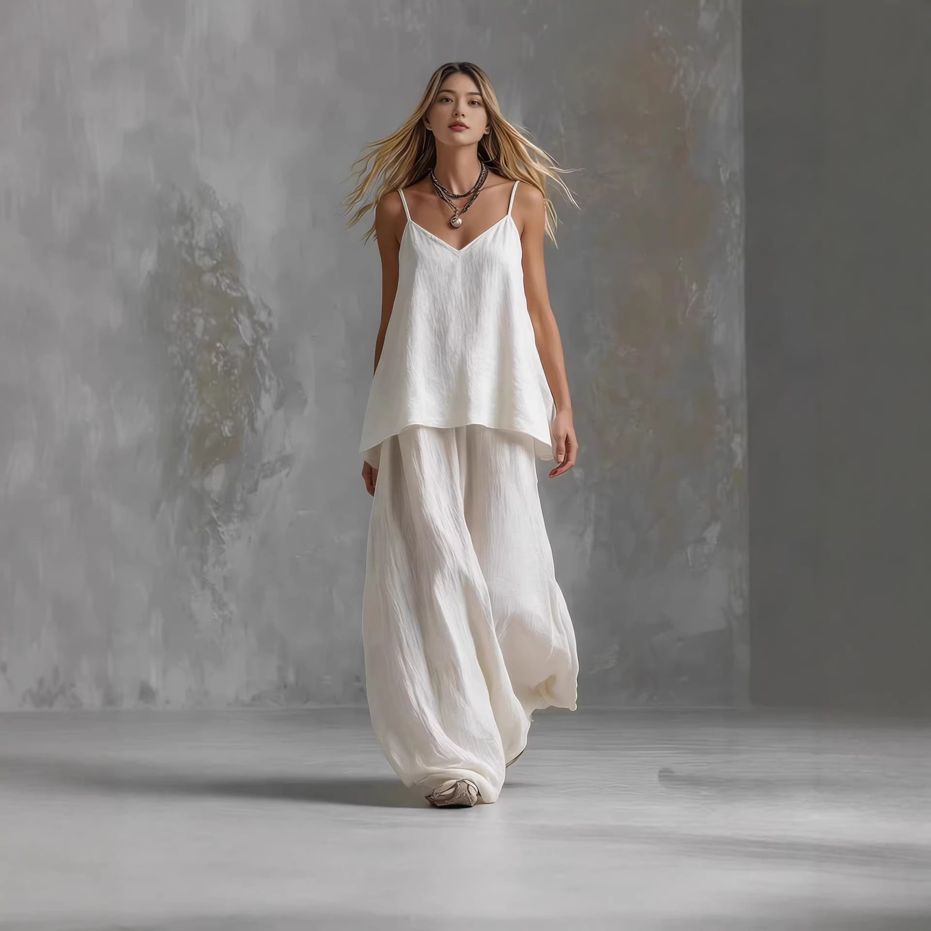 A woman modeling a loose-fitting two-piece set with a v-neck camisole and flowy wide-leg pants in black and white options.