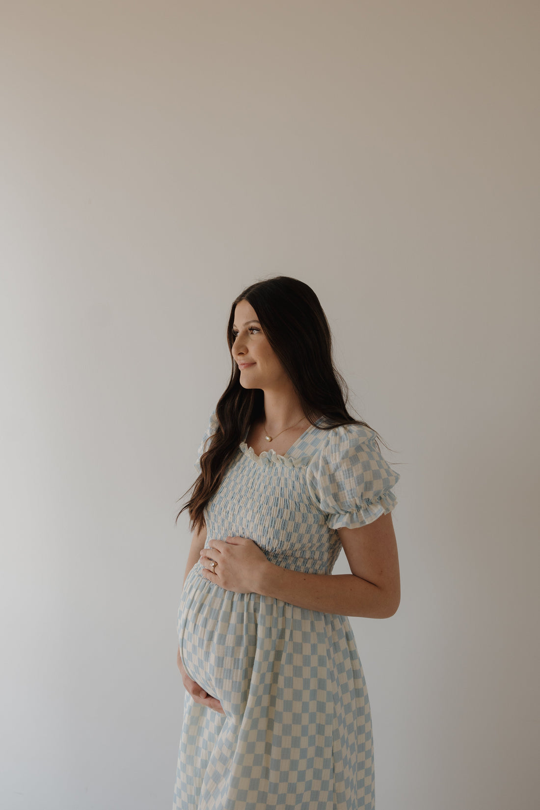Woman wearing a light blue and cream checkerboard print midi muslin dress