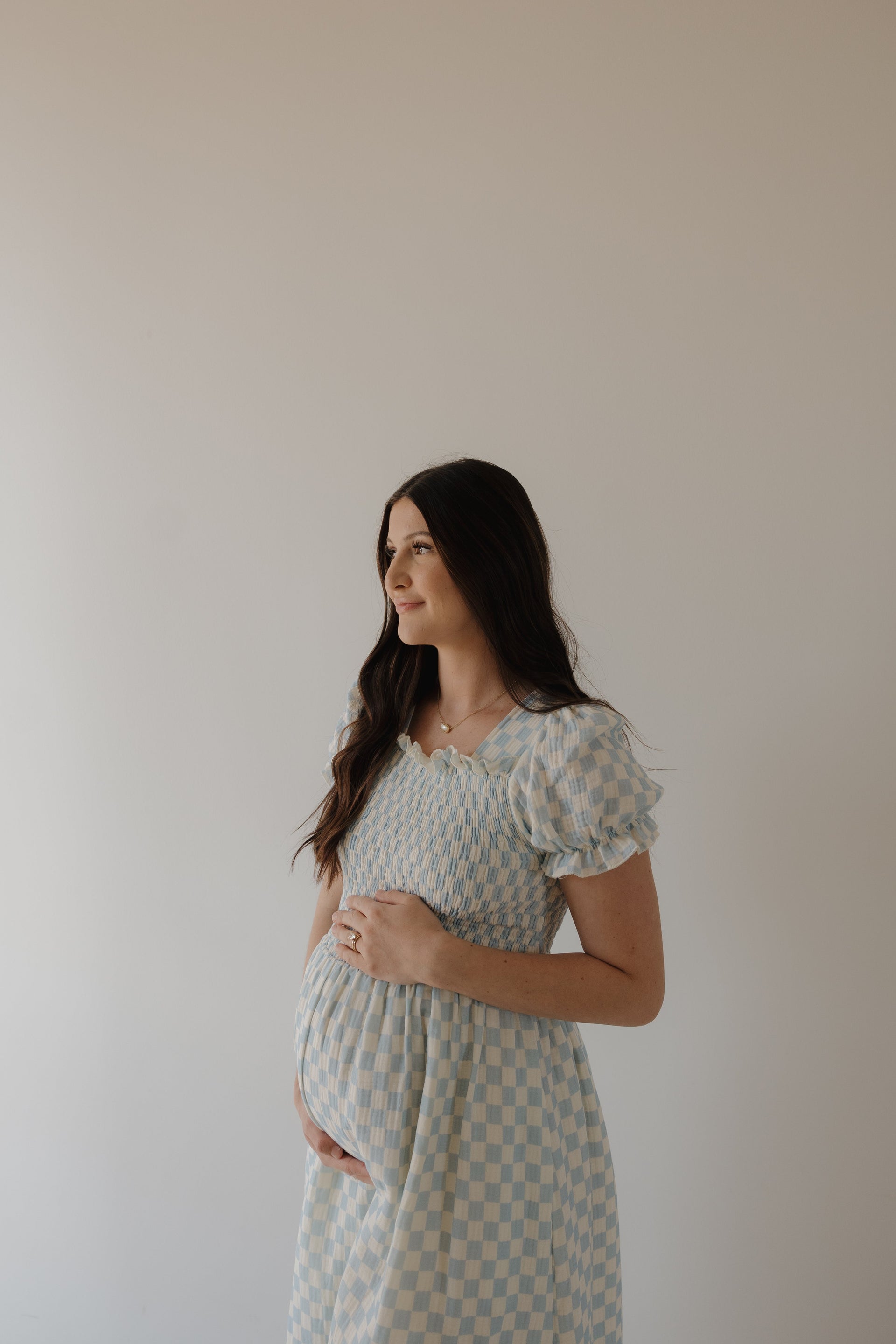 Woman wearing a light blue and cream checkerboard print midi muslin dress