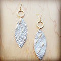 White and gold gator-embossed oval leather earrings hanging from hammered matte gold-tone hoops.