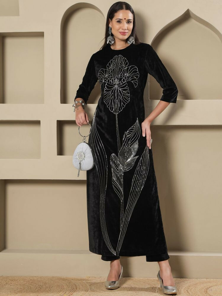 Woman wearing a black velvet kurta set with detailed hand embellishments.