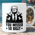 White ceramic coffee mug featuring a graphic of Donald Trump wearing American flag sunglasses and giving the middle finger with text that reads You Missed So Bigly