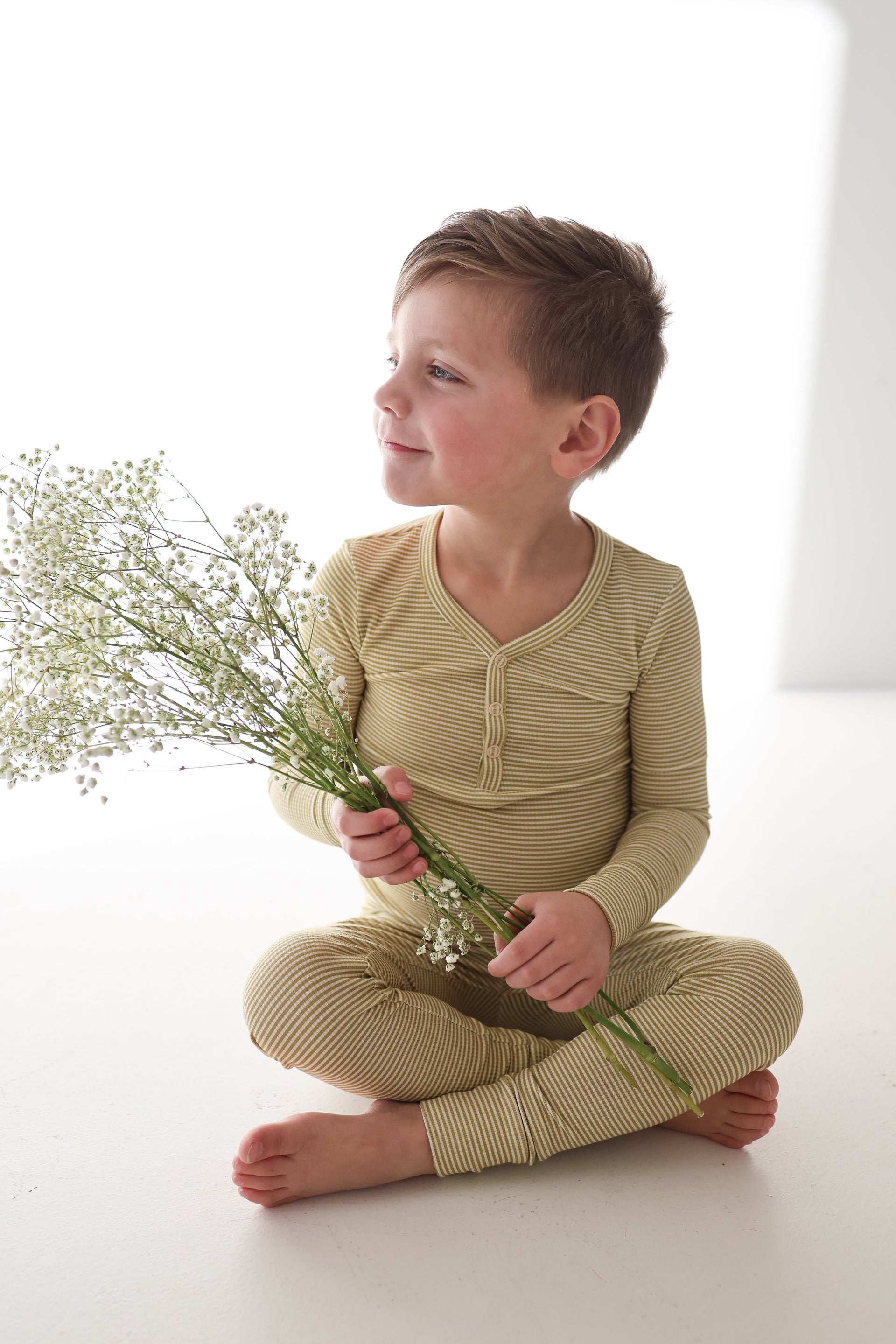 Young boy sitting on the floor wearing Willow Stripe ribbed bamboo two-piece pajamas